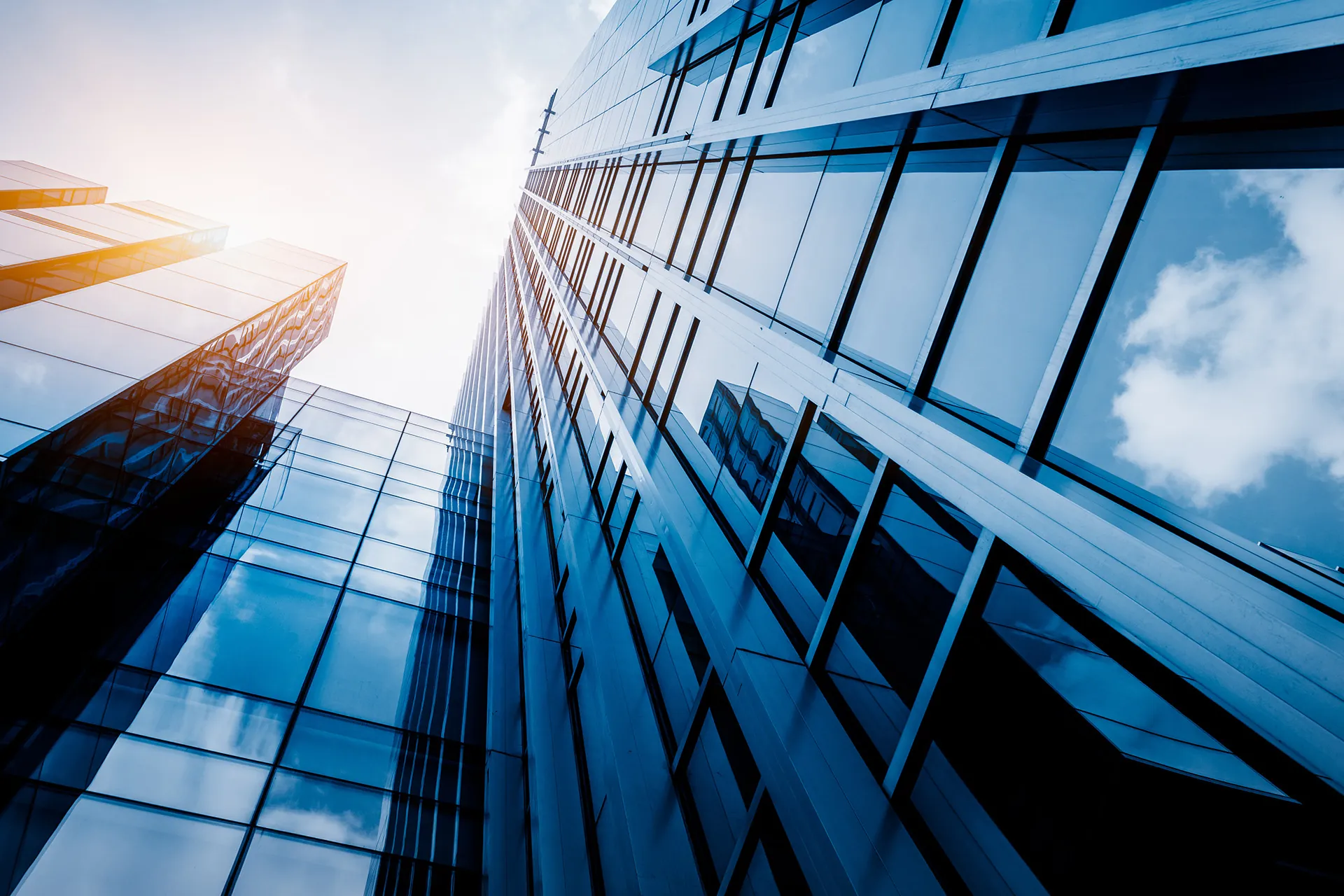 Glass office towers photographed looking upward against a bright sky